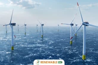 "Offshore wind turbines in the ocean, with white poles and red-tipped blades,